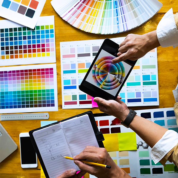 A person holding a tablet over a range of colour selection tools